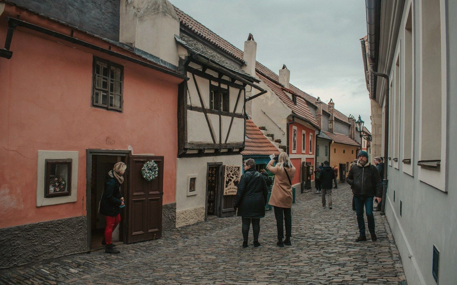 Exterior of the small houses on Zlatá ulička (Golden Lane) inside Prague Castle, stone walls, low doorways, grey morning light